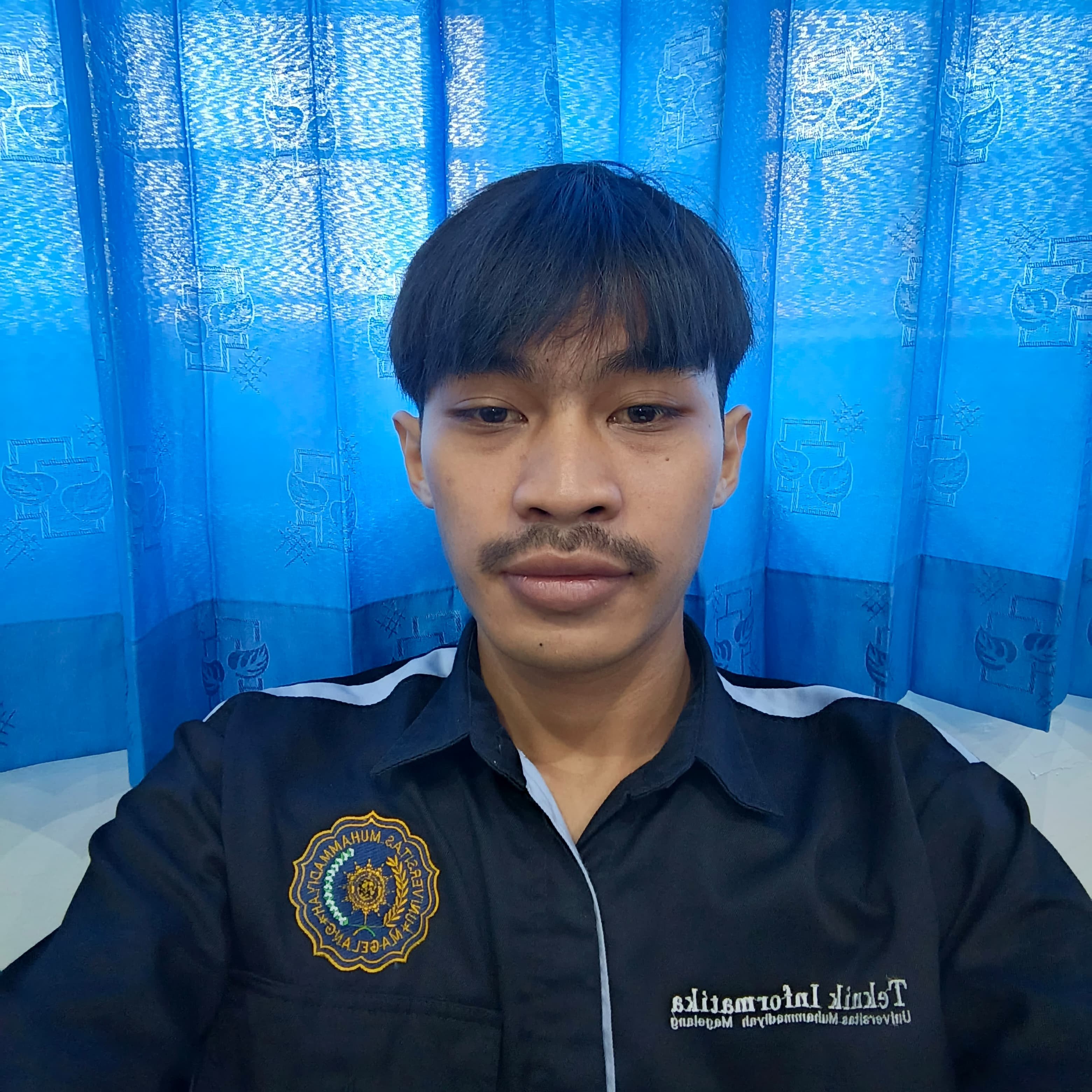 Mahasiswi Teknik Informatika UNIMMA wanita memakai hijab merah muda sedang duduk di lab komputer